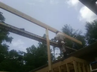 Carpenter setting a ridge beam over a new addition frame — Ice Dam Removal by Roofing Brothers in Riley