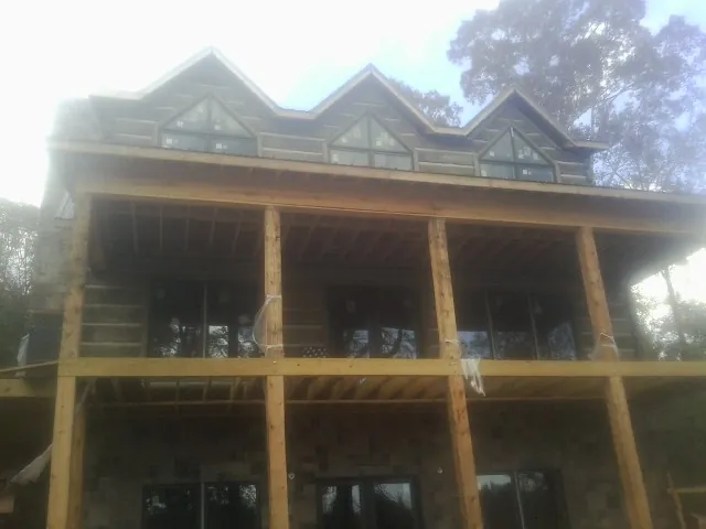 Dormers and porch framing on a large log home under construction — Roof Coating work by our crew in Riley