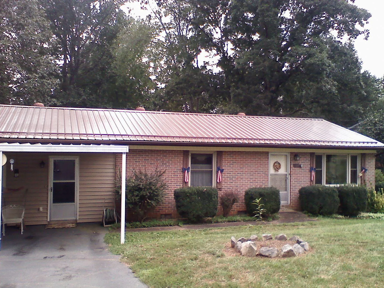 Bronze metal roof and carport on a brick ranch home — Roof Repair work by our crew in Riley