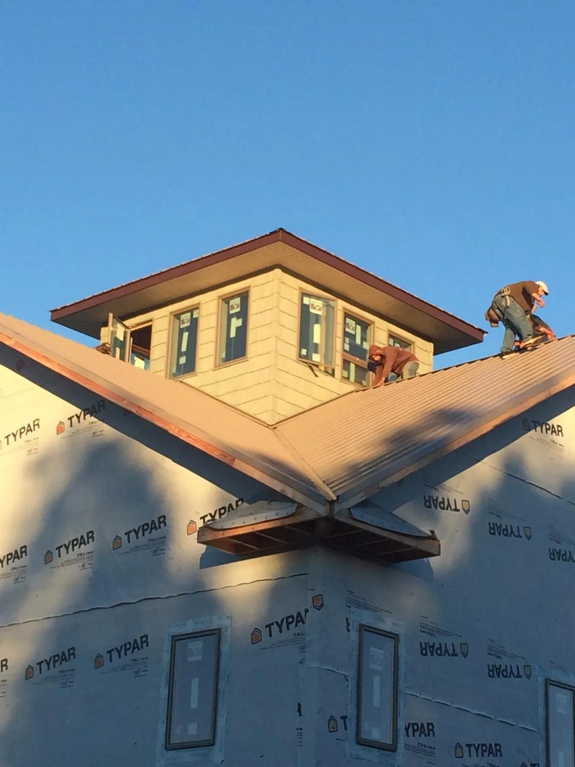 Roofers working around a rooftop cupola on a new metal roof at sunset — Roof Waterproofing in Riley by Roofing Brothers